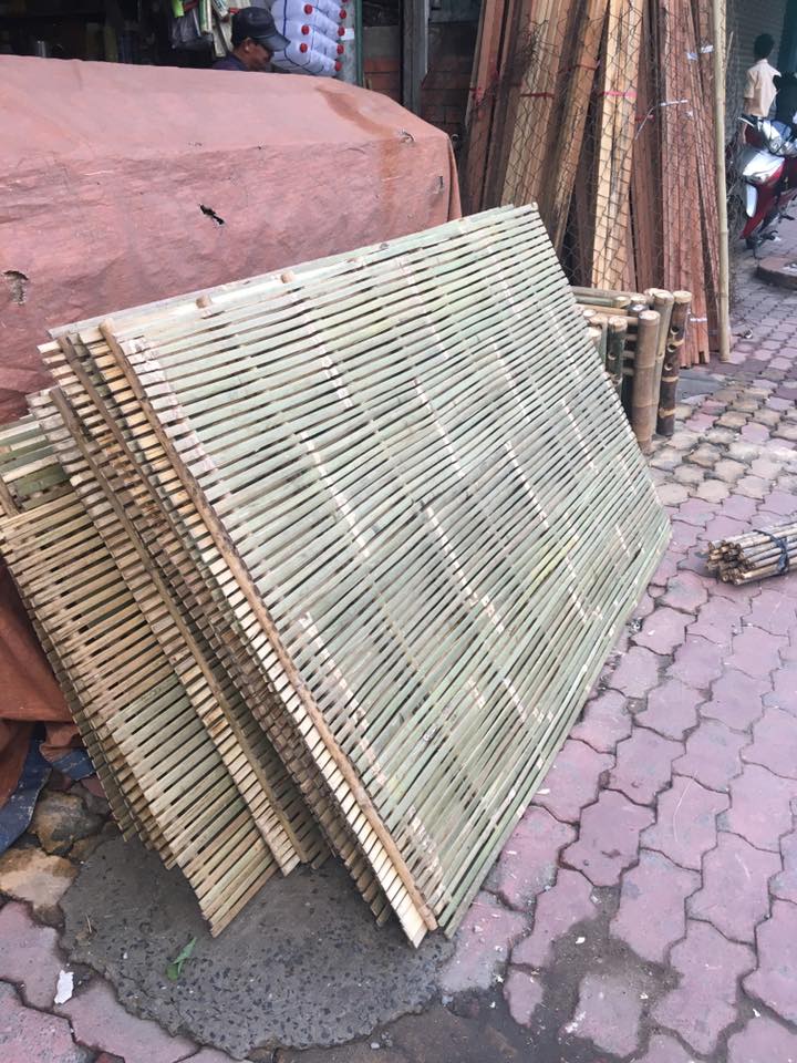 Chồng dát giường bằng tre, màu xanh nhạt, đang được bày bán trên vỉa hè.