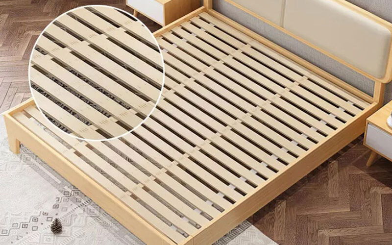 dát giường gỗ truyền thống với các thanh nan gỗ sáng màu, được lắp đặt trong một chiếc giường ngủ phong cách tối giản.