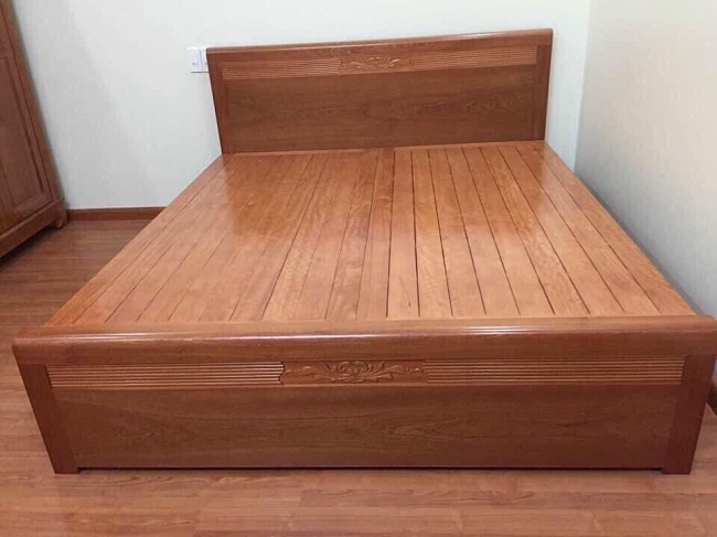 dát giường phản gỗ xoan đào liền khối, có vân gỗ đẹp, trong một chiếc giường ngủ gỗ truyền thống.