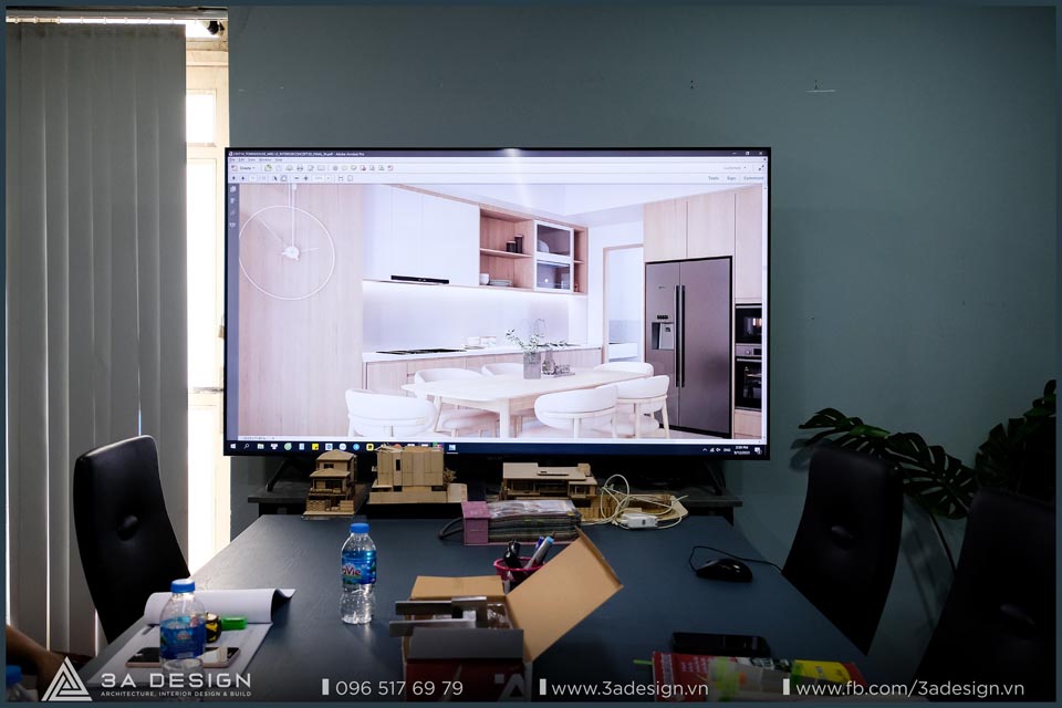 Màn hình lớn trong phòng họp 3A Design hiển thị bản thiết kế nội thất phòng bếp hiện đại, xung quanh là bàn làm việc với tài liệu và mẫu vật liệu.