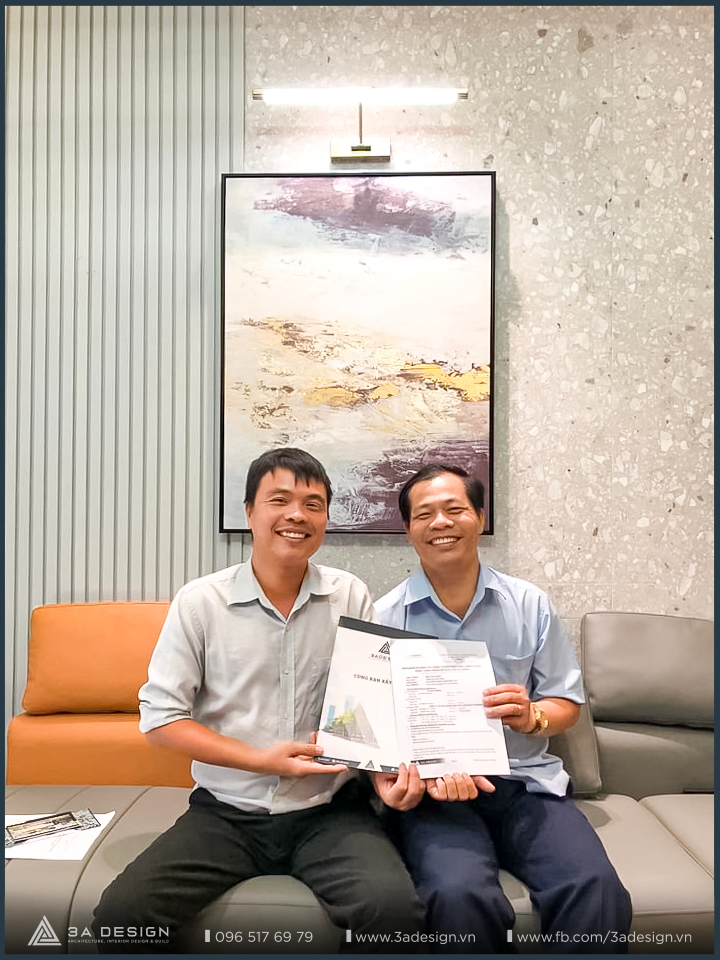 Khách hàng tươi cười cầm biên bản bàn giao công trình cùng đại diện 3A Design, thể hiện sự hài lòng và tin tưởng sau khi dự án hoàn thành.