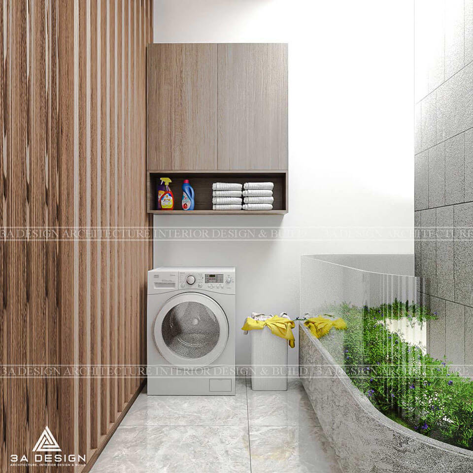 Khu vực giặt đồ nhỏ gọn, có hai máy giặt, kệ gỗ treo tường, giỏ đựng đồ màu xanh ngọc lam, và sàn lát gạch sáng.