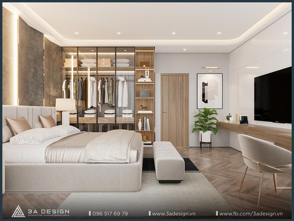 nội thất phòng ngủ hiện đại với giường bọc nệm màu be, tủ quần áo lớn có cửa kính và khu vực bàn làm việc. Phòng được trang trí với tông màu trung tính.