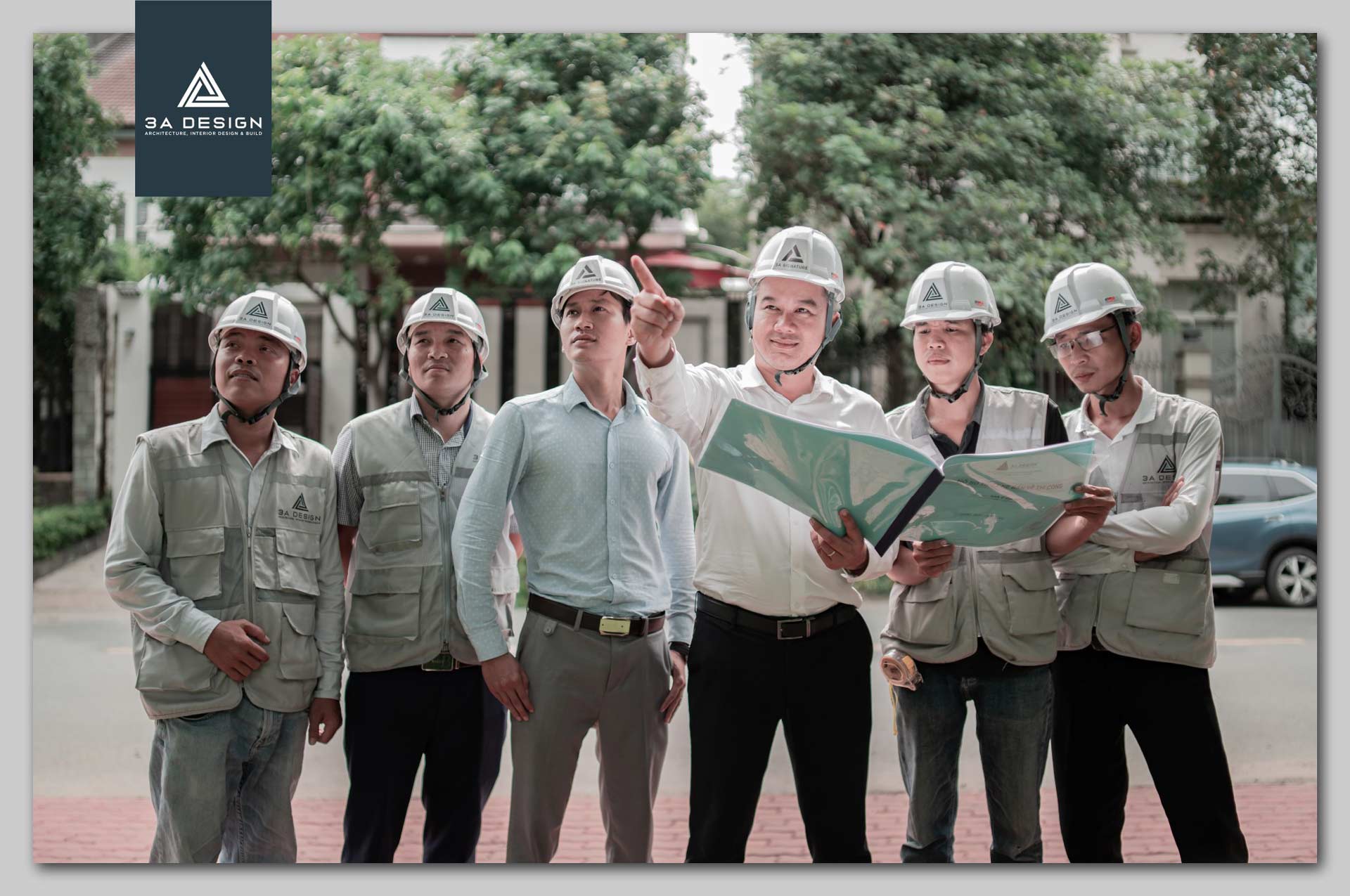Nhóm kiến trúc sư và kỹ sư 3A Design đội mũ bảo hộ, đang trao đổi bản vẽ tại công trình, thể hiện tinh thần làm việc chuyên nghiệp và tận tâm.